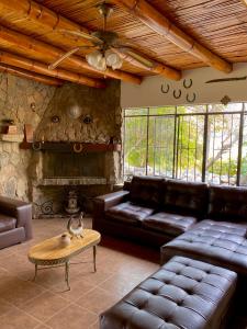 sala de estar con muebles de cuero y chimenea de piedra. en Las Cabañas de Incahuasi en Lunahuaná