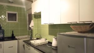 Una cocina con paredes de azulejos verdes y un fregadero. en Departamento La Serena 104, en La Serena