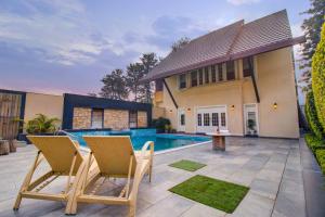 a backyard with a pool and two chairs and a house at Stay Vista at Ekant Villa - 3BR in Amritsar