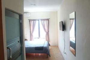 - une chambre avec un lit, un miroir et une fenêtre dans l'établissement bumimakhraja syariah 4, à Bandung
