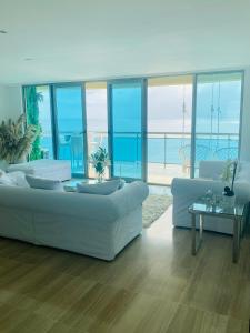 uma sala de estar com mobiliário branco e vista para o oceano em Malecón vista mar Habitación Privada Larimar, em Santo Domingo