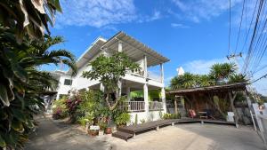 a white house with a porch with trees and plants at Sawaddeethaweesuk At Kohlarn in Ko Larn