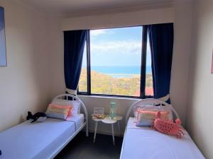 two beds in a room with a large window at Wirrina Cove Apartment in Wirrina Cove