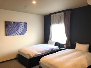 a bedroom with two beds and a window at HOTEL COLLECT in Sakai