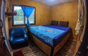 um pequeno quarto com uma cama e uma cadeira em แพแหม่มทัวร์ em Sai Yok