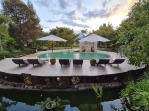 a pool with chairs and umbrellas on a wooden deck at Pai My Guest Resort - SHA Plus in Pai