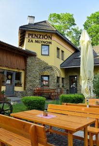 una mesa de madera con una sombrilla frente a un edificio en Penzion za mlynom, en Liptovská Teplá