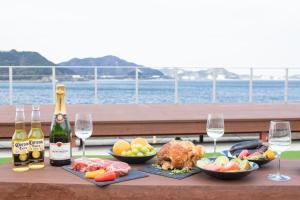 una mesa con botellas y copas de vino y comida en オーシャンヴィラ鳴門-Ocean Villa Naruto-, en Naruto