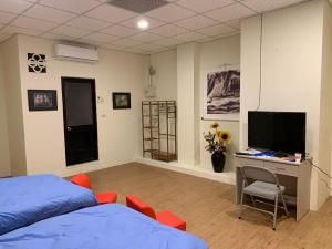a bedroom with a bed and a desk with a television at Yataku 雅德背包客舍 in Puli