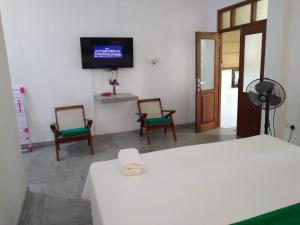 a room with a bed and two chairs and a tv at MN House in Unawatuna