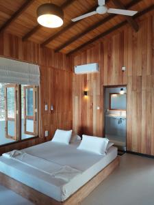 een groot bed in een kamer met houten wanden bij Mountain Wave Hotel and Surfshop in Hikkaduwa