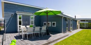 a patio with a table and a green umbrella at luxe cottage knokke heist in Knokke-Heist