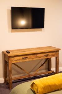 a wooden table with a television on a wall at The Salty Bushman B&B in Kaka Point