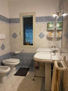 a bathroom with a sink and a toilet and a window at Trilocale Piazza Italia Orosei - IUN Q5292 in Orosei