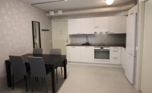 a kitchen with a black table and white cabinets at Teemahostel in Toivakka