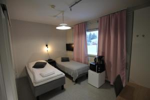 Teemahostel في Toivakka: غرفة صغيرة بسريرين ونافذة