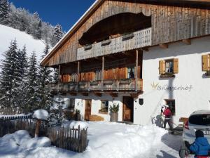 a building in the snow with a person standing in front of it at Bruggerhof Prags in Braies