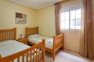 a bedroom with two beds and a window at Playa Golf 2 in Cabo Roig