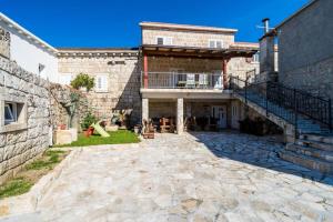 uma vista exterior de uma casa com um pátio de pedra em Guest House Godimento em Cilipi