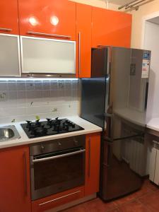 a kitchen with orange cabinets and a stove and a refrigerator at 1к. Апартаменты НСК , на ул.Ватутина 24 in Novosibirsk