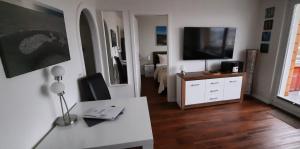 ein Wohnzimmer mit einem TV und einem weißen Tisch in der Unterkunft Ferienwohnung Austernmuschel in Westerland