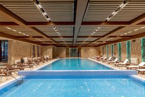 a large swimming pool with chairs and a swimming poologgle at Wyndham Garden Burabay in Borovoye