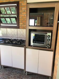 a kitchen with a stove and a microwave at Casa Tijolinho a Vista - 150 mt praia in Governador Celso Ramos