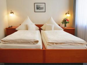 2 Betten mit weißer Bettwäsche und Kissen in einem Zimmer in der Unterkunft Hotel Martha Dresden in Dresden