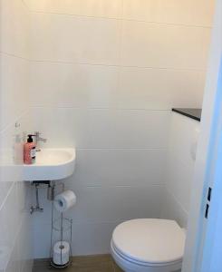 een witte badkamer met een toilet en een wastafel bij Witte Jade in Egmond aan den Hoef