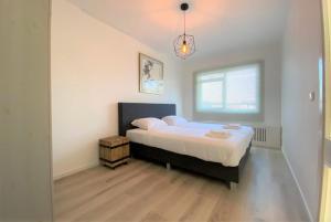 een slaapkamer met een groot bed met witte lakens en een raam bij Witte Jade in Egmond aan den Hoef