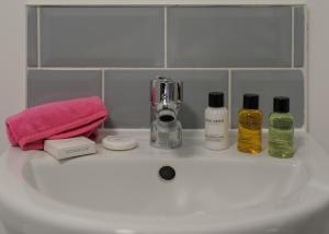a bathroom sink with three bottles of soap and a mixer at Donington Cottage Apt 7 in Castle Donington