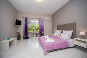 a bedroom with a pink bed and purple curtains at Sunset Apartments in Archangelos