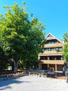 a building with a tree and flowers in front of it at Hotel Landgasthof Fromm in Untergruppenbach