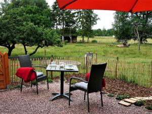 una mesa con 2 sillas y una sombrilla roja en Schäfchenwolke, en Worpswede