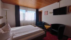 a bedroom with a bed and a television and a chair at Hotel Landgasthof Fromm in Untergruppenbach