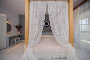 a canopy bed with white curtains in a room at Sunset Apartments in Archangelos