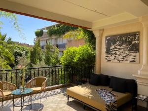 einen Balkon mit einem Sofa, einem Tisch und Stühlen in der Unterkunft Les Jardins De La Koutoubia in Marrakesch