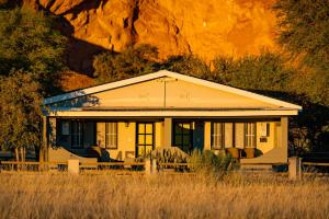 Gondwana Namib Desert Lodge في سوليتير: منزل اصفر صغير وسط الميدان