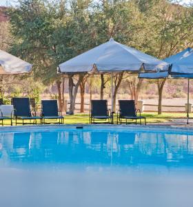 a swimming pool with chairs and umbrellas at Gondwana Namib Desert Lodge in Solitaire