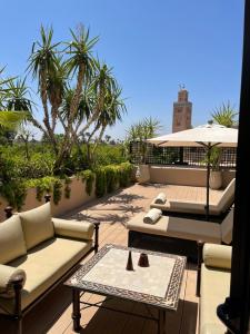 eine Terrasse mit Sofas, einem Tisch und einem Sonnenschirm in der Unterkunft Les Jardins De La Koutoubia in Marrakesch