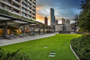 a building with a lawn with chairs and a city at Southbank Apartments Freshwater Place in Melbourne