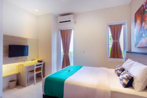 a bedroom with a bed and a desk and a television at Nivasa Nusa Dua in Ungasan