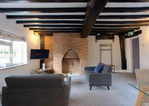 a living room with couches and a brick fireplace at Donington Cottage Apt 8 in Castle Donington