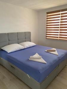 ein Bett mit blauer Bettwäsche, weißen Kissen und einem Fenster in der Unterkunft Villa Lovric in Marina