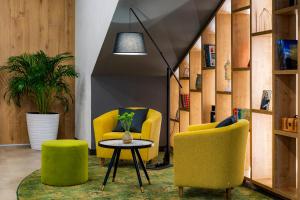 a living room with two yellow chairs and a table at The Gate Hotel City Centre in Tbilisi City