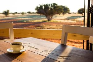a cup of coffee sitting on top of a wooden table at Gondwana Kalahari Anib Lodge in Hardap