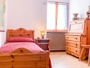 een slaapkamer met een houten bed, een dressoir en een raam bij APPARTAMENTO CASANOVA in Andalo
