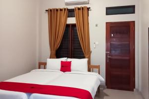 ein Schlafzimmer mit einem großen weißen Bett mit roten Kissen in der Unterkunft RedDoorz At Joyce Guest House Medan in Medan