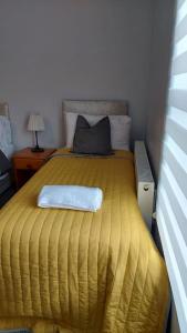 a bedroom with a bed with a yellow comforter at White Shelf West Dartford in Kent