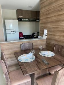 a wooden table with two plates and wine glasses on it at Vg Sun cumbuco 310 c4 in Cumbuco